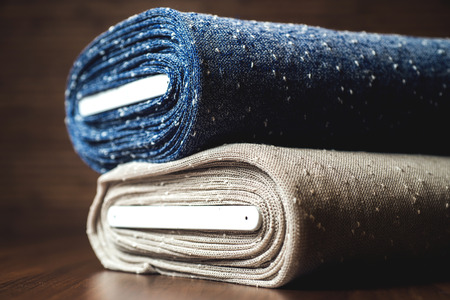 Rolls of blue and brown fabric on wooden .