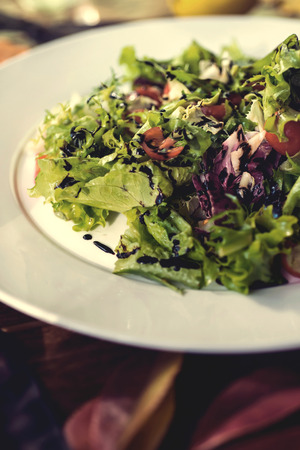 Fresh salad with lettuce and tomatoes on a plate on wooden .の写真素材