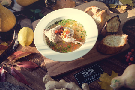 A picture of a bowl of traditional chicken soup served in a bowl over wooden backgroundの写真素材