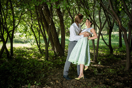 Wedding couple, beautiful young bride and groom standing in a park outdoors holding hands ,smiling.の写真素材
