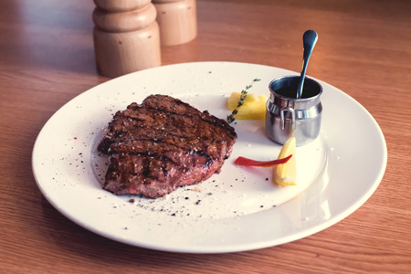 Grilled steak with pineapple, pepper, rosemary and tomato sauce on the wooden table.の写真素材