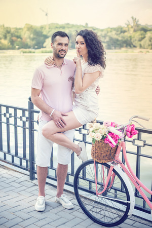 Couple with pink vintage bicycle in the summer park on a sunsetの写真素材