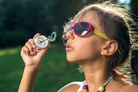 Cute little girl is blowing a soap bubbles