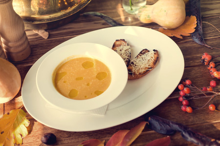 Bowl of pumpkin soup with bread crouton on white wood tableの写真素材