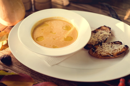 Bowl of pumpkin soup with bread crouton on white wood tableの写真素材