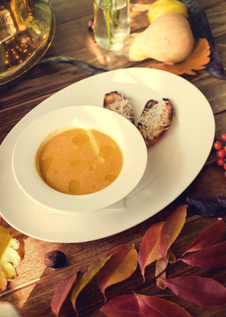 Bowl of pumpkin soup with bread crouton on white wood tableの写真素材