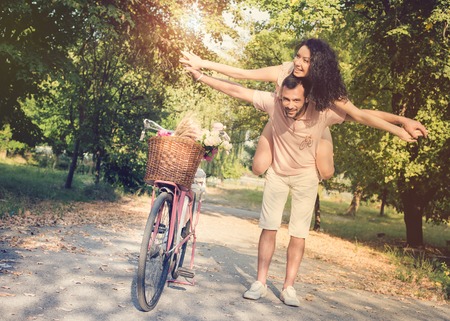 Couple with pink vintage bicycle in the summer park on a sunsetの写真素材