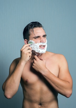 Young man shaving with hate and aggression.の写真素材