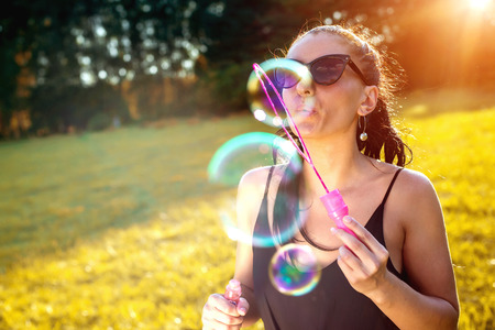 Cute girl is blowing a soap bubbles.の写真素材