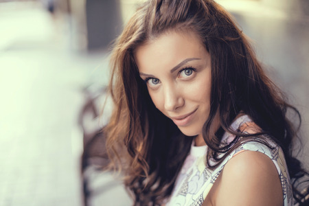 sensual woman posing with big eyes and full lips at evening sunlight at city park.
