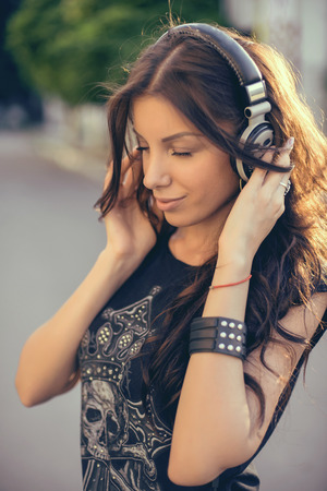 Young beautiful girl listening to MP3 player on the street.の写真素材