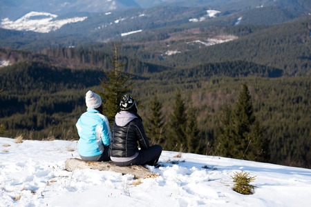 girls enjoying mountain view together in wintertimeの写真素材