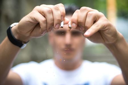 Young attractive man breaking cigarette.の写真素材