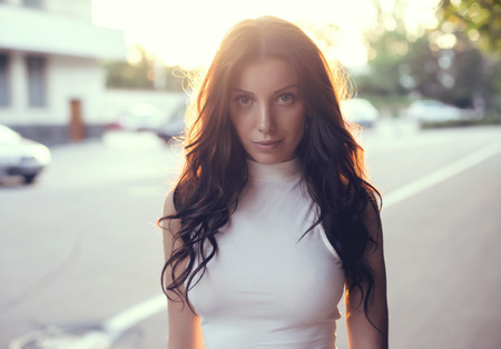 Sexy sensual woman posing with big eyes and full lips at evening sunlight in city park.の写真素材