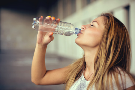 Portrait of woman drinking water outdoor .の写真素材