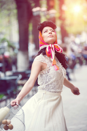 woman spinning around on the street with a can and basket with eggsの写真素材