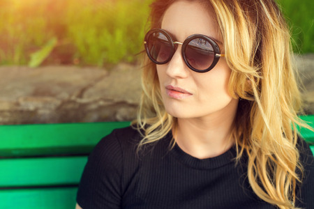 Portrait of a girl in sunglasses with a paper cup of coffee . Shooting at sunsetの写真素材