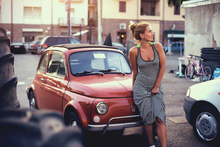 Young woman in stylish dress standing near her little retro car. Italy.の写真素材