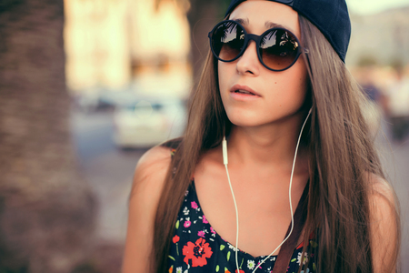 Beautiful girl listening to music. background of the street.の写真素材