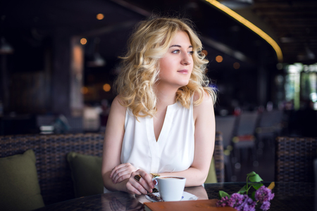 Successful and wealthy business woman having cup of espresso coffee while sitting in a restaurant terrace.の写真素材