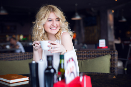 Successful and wealthy business woman having cup of espresso coffee while sitting in a restaurant terrace.の写真素材