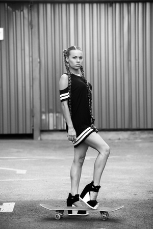 young pretty girl using skateboard on the street, hipster style, outdoor beauty portraitの写真素材