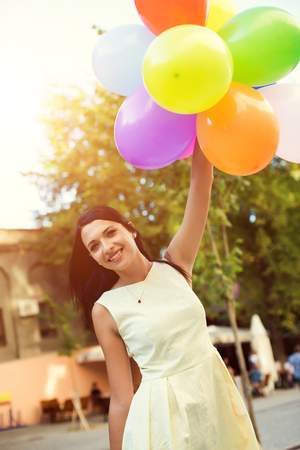 Happy young woman with colorful latex balloons, outdoor.の写真素材