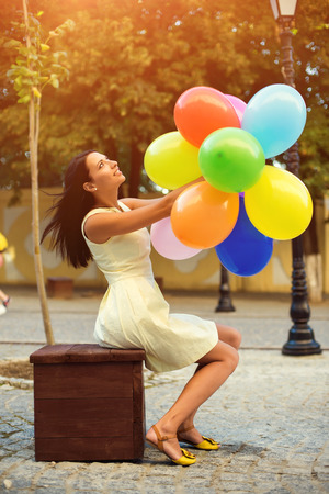 Happy young woman with colorful latex balloons, outdoor.の写真素材