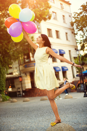 Happy young woman with colorful latex balloons, outdoor.の写真素材