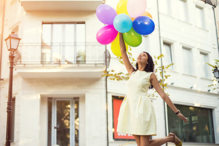 Happy young woman with colorful latex balloons, outdoor.の写真素材