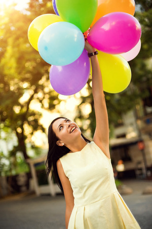 Happy young woman with colorful latex balloons, outdoor.の写真素材