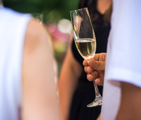 Men's hand holding wine champagne at festive event.の写真素材