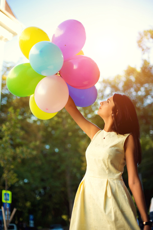 Happy young woman with colorful latex balloons, outdoor.の写真素材