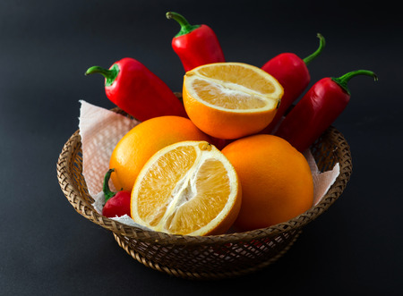 A beautiful basket with oranges and red chilli peppers.の写真素材