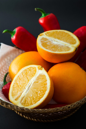 A beautiful basket with oranges and red chilli peppers.の写真素材