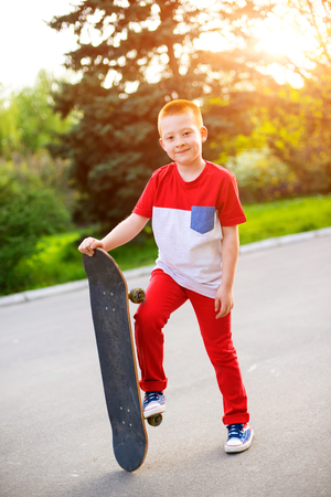 Cool 7 year old boy with his skateboard on the street. Childhood. Summertimeの写真素材