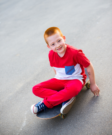 Cool 7 year old boy with his skateboard on the street. Childhood. Summertimeの写真素材