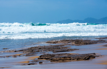 Blue Fresh Water Whitecap Waves Wash Ashore onto a Sandy Beachの写真素材