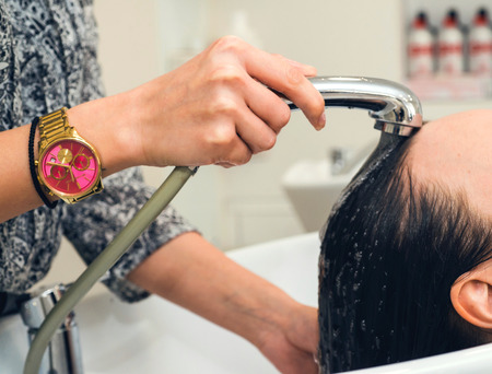 Barber washes the girls head in the barbershopの写真素材