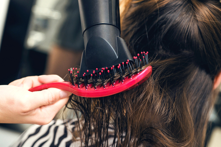 Drying long brown hair with hair dryer and brush. Close-up.の写真素材