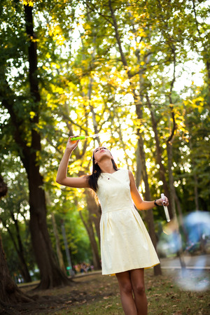 beautiful young woman with yellow dress blowing bubble in the cityの写真素材