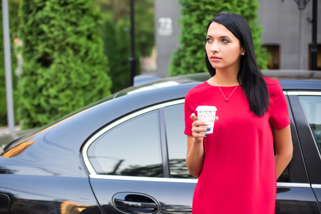 Young stylish woman drinking coffee to go in a city streetの写真素材