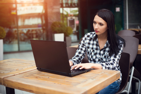 Happy sitting woman working with her laptop in an terraceの写真素材