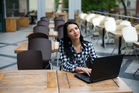 Happy sitting woman working with her laptop in an terrace.の写真素材