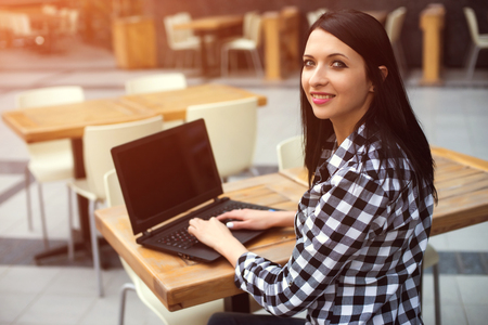 Happy sitting woman working with her laptop in an terrace.の写真素材
