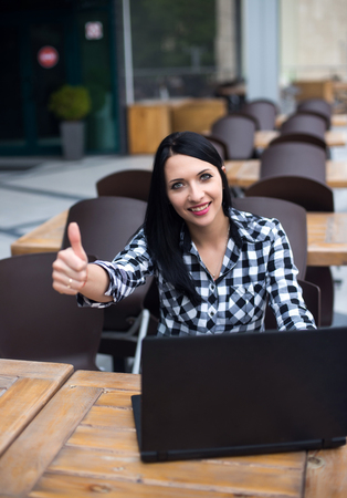 Happy sitting woman working with her laptop in an terrace.の写真素材