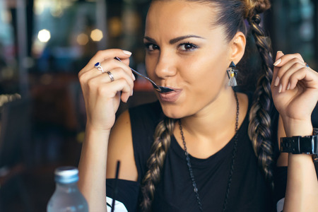 Woman with pigtails drinking coffee in trendy cafeの写真素材