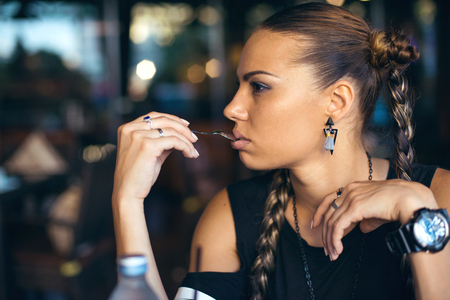 Woman with pigtails drinking coffee in trendy cafeの写真素材