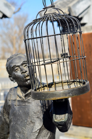 Statue of a man holding an empty bird cageの写真素材