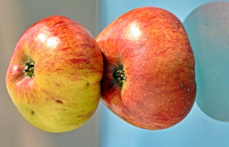 two apples stacked on top of each other, isolated against a blue, brown background.の写真素材